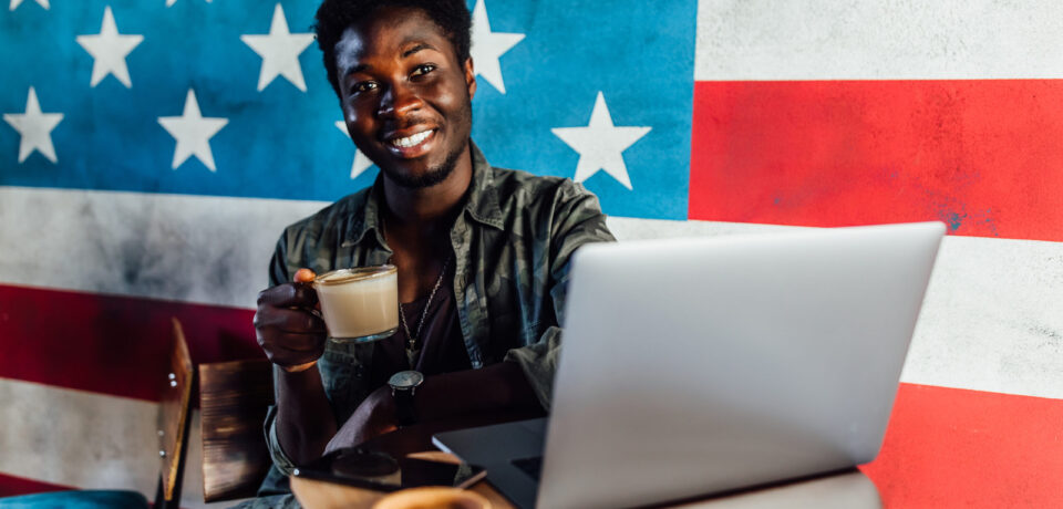 Photo of happy african man sitting in a cafe and working on laptop , have a coffe break..